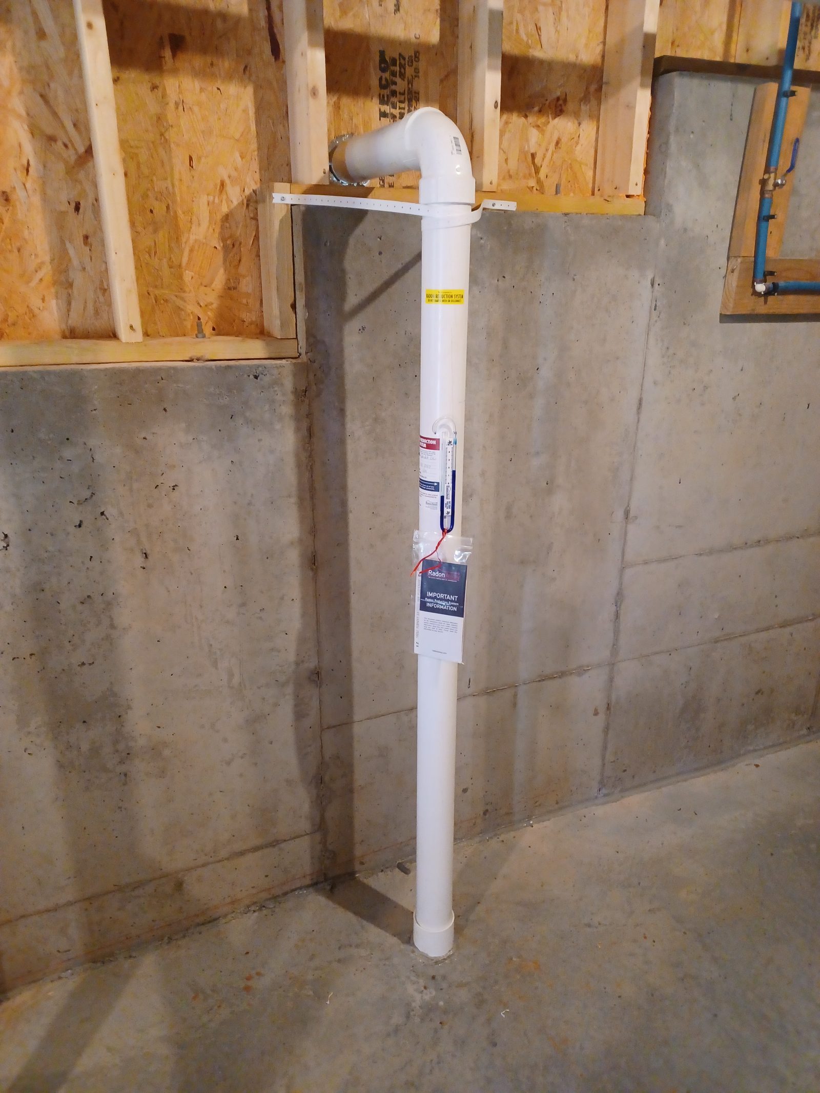 Radon mitigation riser installed against a basement foundation wall